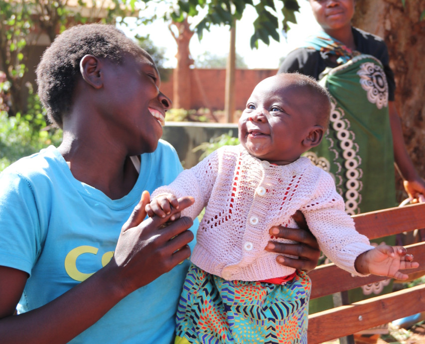 The first child to receive the malaria vaccine is smiling at her mother.