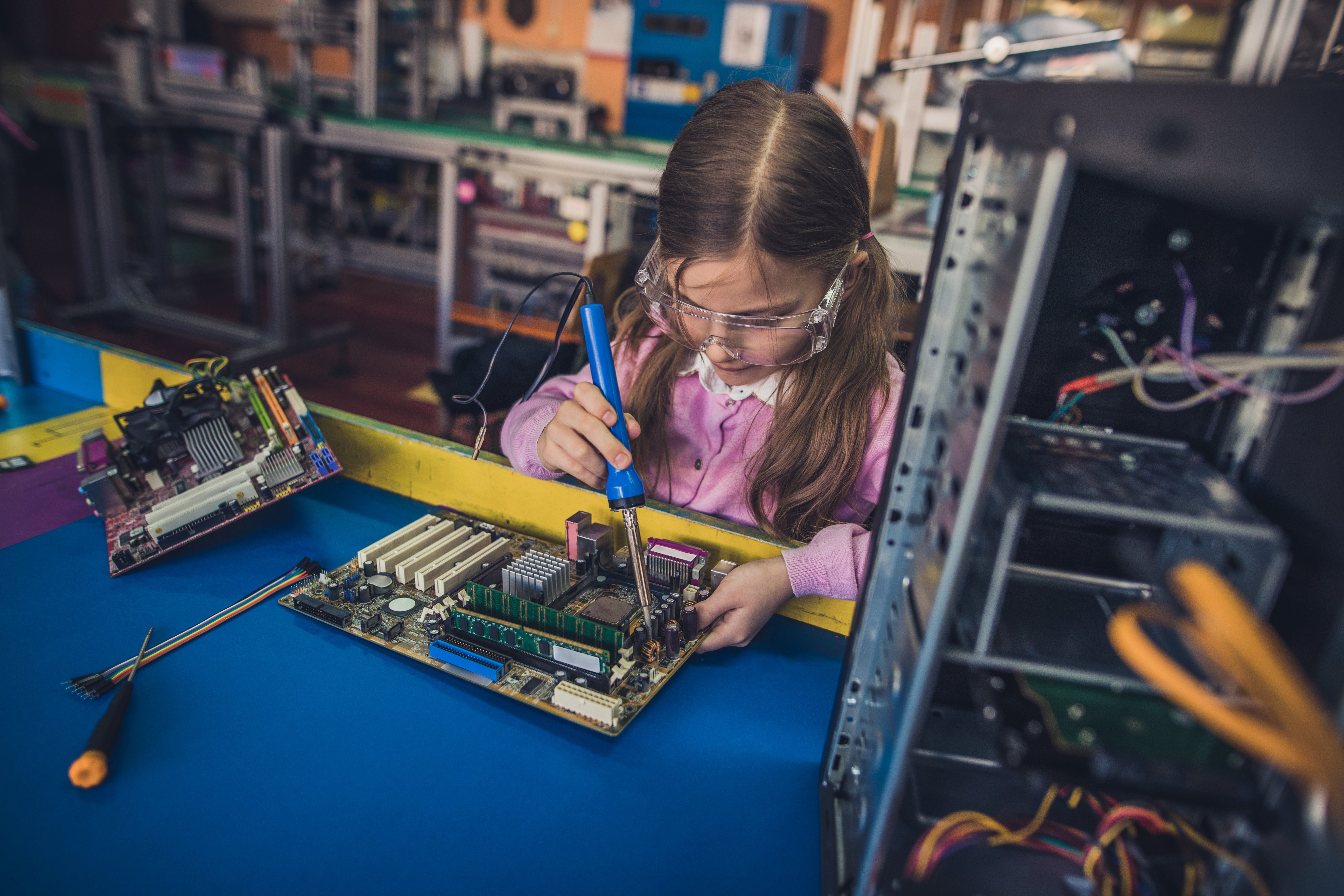 Focused girl soldering mother board in a laboratory.